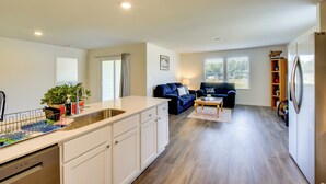 A modern kitchen with a built-in island, a dining area with a blue sofa, and a living room with a dark blue sofa. - Lake Hartwell Home Base: 2 Mi to Marina! (Hartwell)