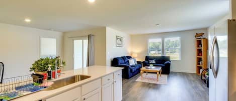 Een moderne keuken met een inbouw eiland, een eethoek met een blauwe bank, en een woonkamer met een donkerblauwe bank.