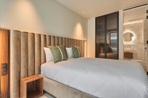 A modern bedroom with a large bed, a wooden bedside table, and a sliding glass door leading to a bathroom. - Sublim Apartment - Le Marais - Beaubourg (Paris)