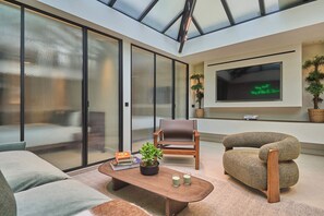 Ein modernes Wohnzimmer mit Sofa, Couchtisch, Fernseher und einem großen Fenster mit Blick.