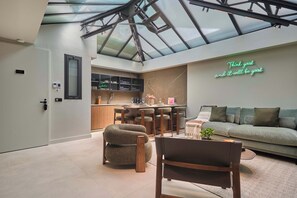 A modern interior with a glass ceiling, a kitchen area, and a living space with a sofa and chairs. - Sublim Apartment - Le Marais - Beaubourg (Paris)