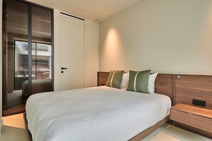 Ein modernes Hotelzimmer mit einem großen Bett, einem Holz-Kopfteil und einem Schiebetürenschrank.