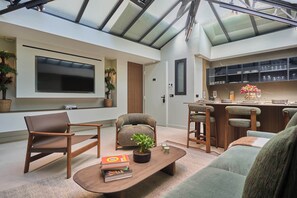 A modern living space with a flat-screen TV, seating area, and a kitchen with bar seating. - Sublim Apartment - Le Marais - Beaubourg (Paris)