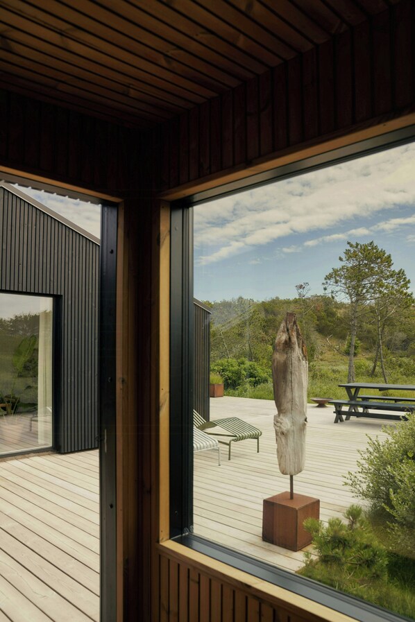 A modern building with a wooden deck, a bench, and a sculpture. - Nordic cottage by Nationalpark Thy (Klitmøller)