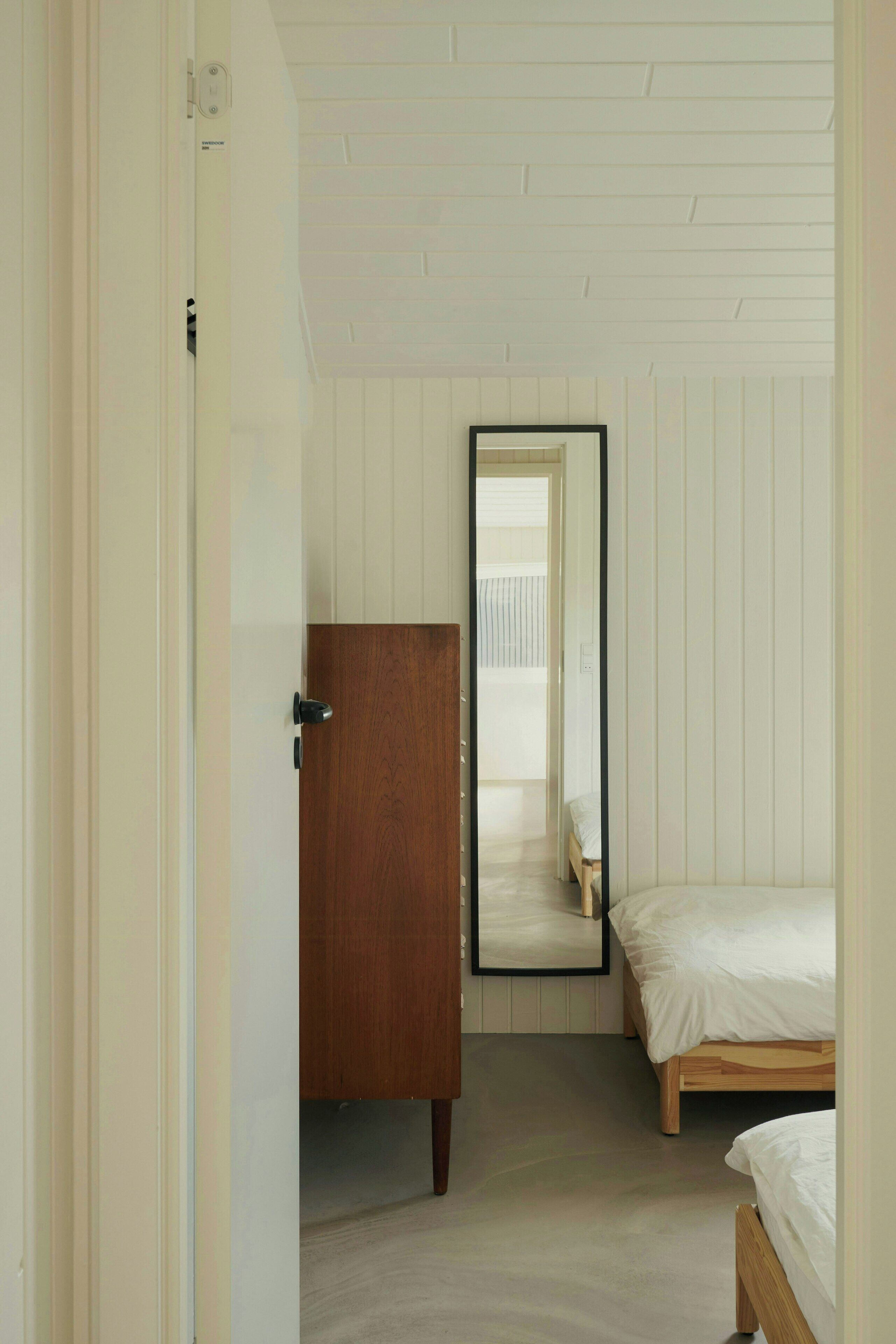 Un dormitorio con un armario de madera, una cama y un espejo en la pared.