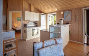 Uma cozinha compacta com armários brancos, um fogão e um espaço de jantar com mesa e cadeiras.