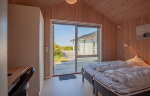 Ein Schlafzimmer mit Bett, Schreibtisch und einer Schiebetür zu einem Außenbereich.