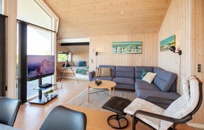 A modern living room with a large flat-screen TV, a sofa, a coffee table, and a chair. - Beach front home in Vestervig with WiFi (Vestervig)