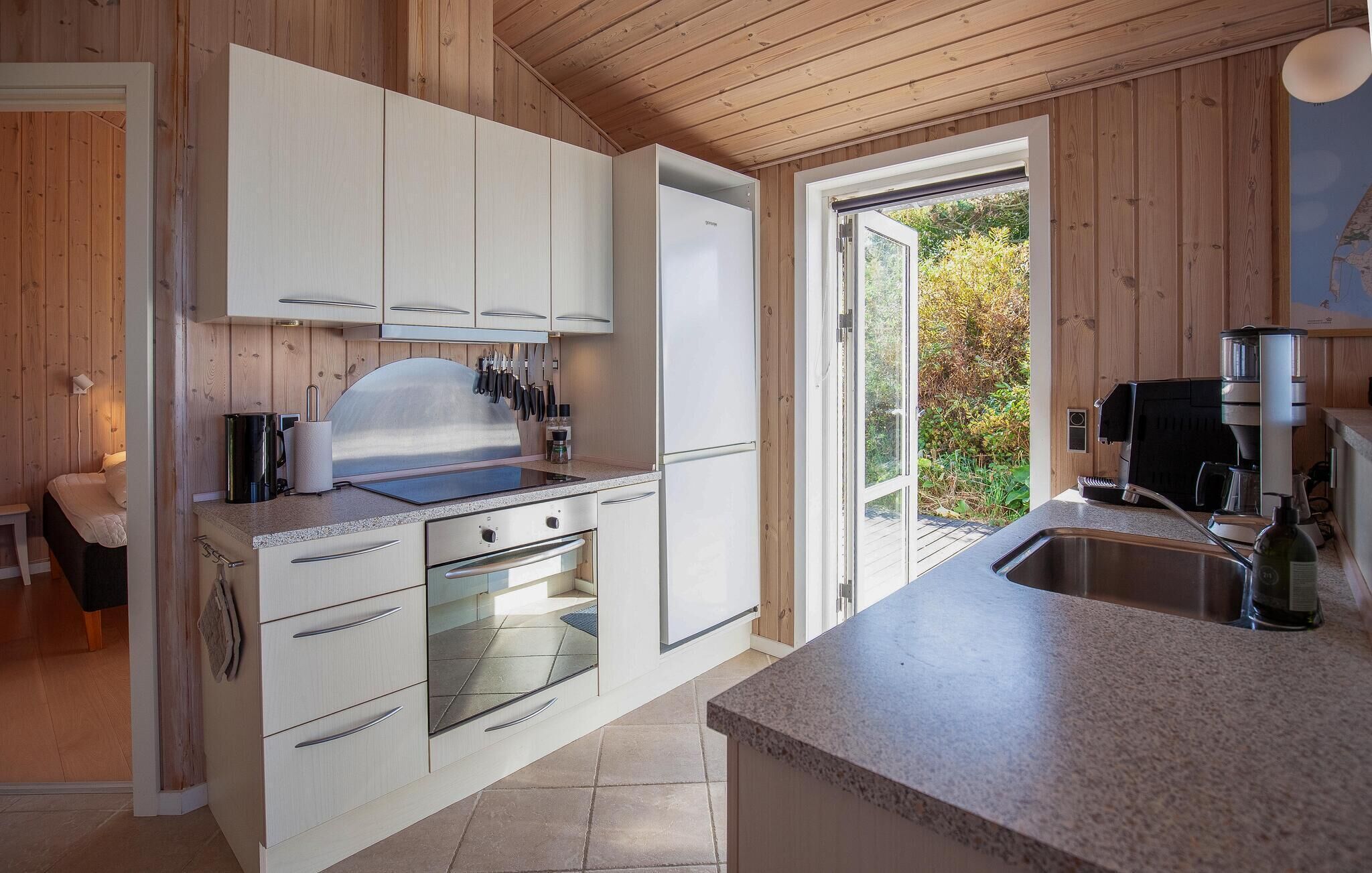 A modern kitchen with white cabinetry, a built-in oven, and a coffee machine.