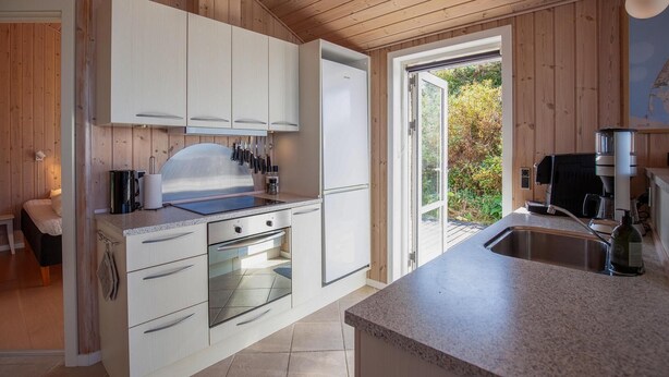 A modern kitchen with white cabinetry, a built-in oven, and a coffee machine. - Beach front home in Vestervig with WiFi (Vestervig)