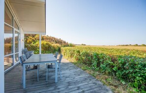 A covered outdoor seating area with a table and chairs, overlooking a field. - Beach front home in Vestervig with WiFi (Vestervig)