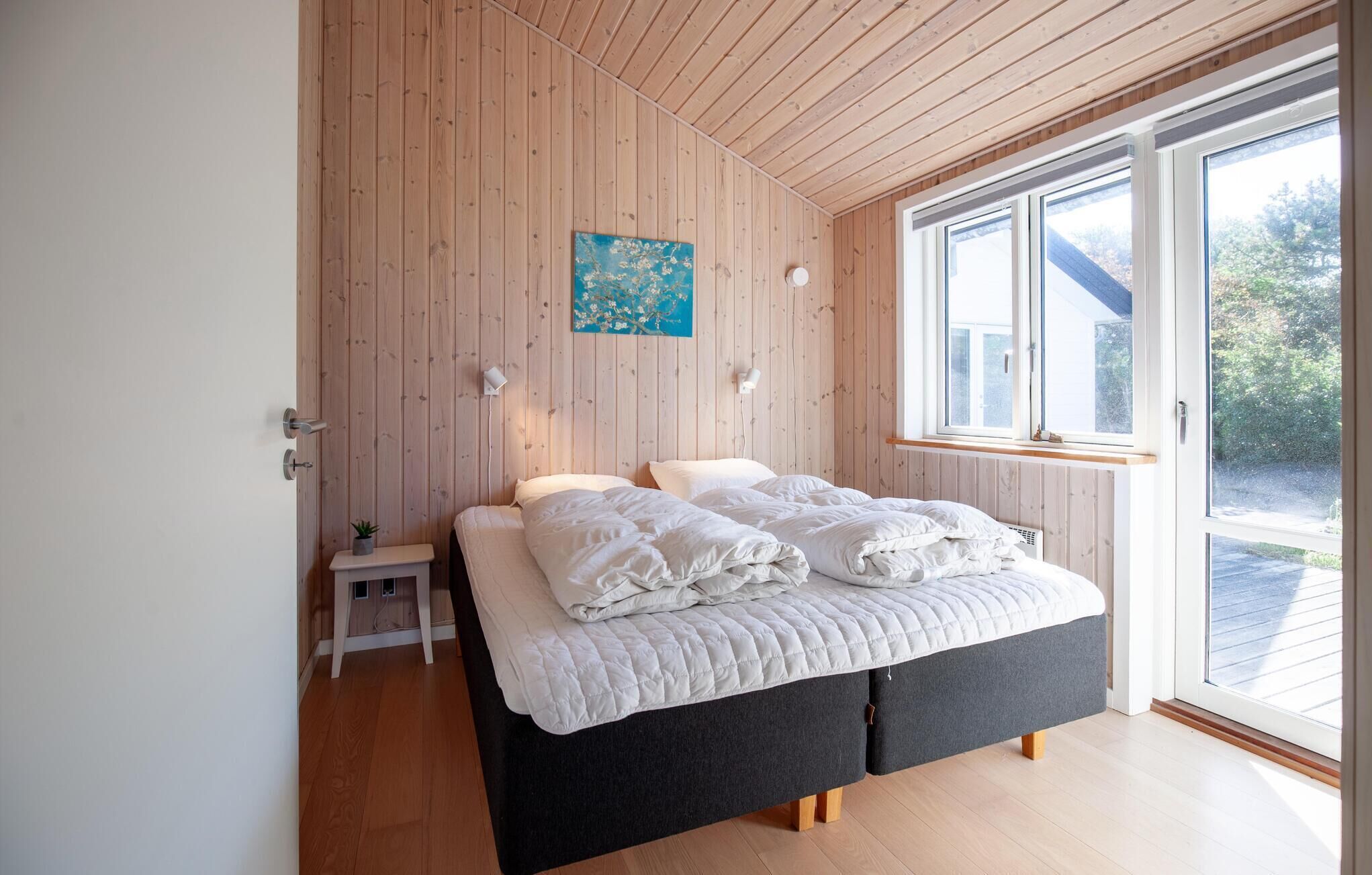 Ein Schlafzimmer mit einem Bett, Nachttischen, einem Gemälde und einem Fenster.