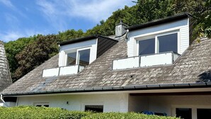 A two-story house with a sloped roof, a chimney, and a white exterior.