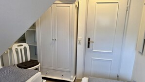 Ein Schlafzimmer mit zwei Einzelbetten, einem Kleiderschrank und einem Stuhl.