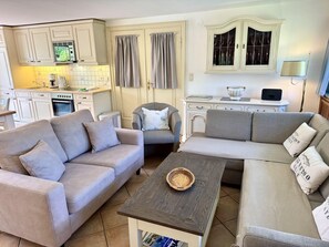 A living room with two sofas, a coffee table, and a kitchen in the background. - Süderstraße, Apartment 01 – Friesenhaus - Frisian 4-room vacation rental for 6 (Sylt)