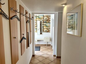 Ein Korridor mit Holztüren, einer weißen Kommode und einem Spiegel an der Wand.
