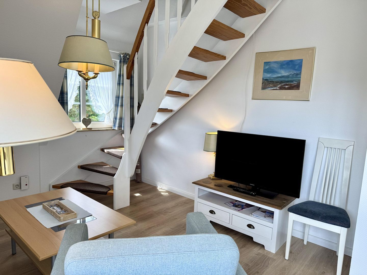 Un salon moderne avec un escalier, un téléviseur à écran plat et un coin repas.
