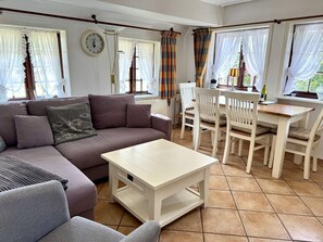 A living room with a sofa, a coffee table, and a dining area with chairs and a table. - Süderstraße, Apartment 03 – Friesenhaus - Cozy 2-room vacation rental for 4 (Sylt)