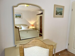 A bedroom with a bed, a bedside table, a mirror, and a door. - Süderstraße, Apartment 03 – Friesenhaus - Cozy 2-room vacation rental for 4 (Sylt)