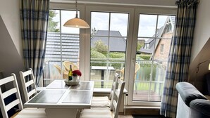 A dining area with a table, chairs, and a hanging light fixture. - Süderstraße, Apartment 07 – Landhaus - Cozy 3-room vacation rental for 4 (Sylt)