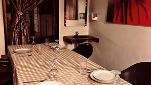 A dining table set with plates, glasses, and cutlery, a mirror on the wall, and a red abstract painting.