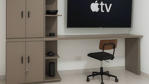 Un ufficio moderno con una televisione a schermo piatto montata a parete, una scrivania e una sedia.