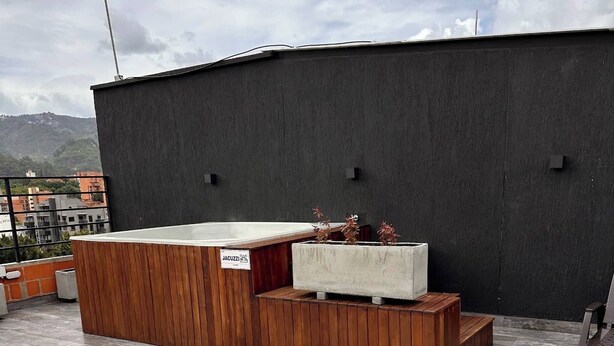 A rooftop terrace with a wooden bench, a concrete planter with plants, and a metal grill. - Luxury Loft  Jacuzzi, Gym and steam bath  Laureles (Medellín)