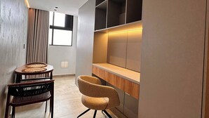 A modern interior with a dining area featuring a round table and two chairs, a built-in wooden desk with shelves, and a large window providing natural light. - Luxury Loft  Jacuzzi, Gym and steam bath  Laureles (Medellín)