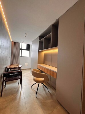 A modern interior with a dining area featuring a round table and two chairs, a built-in wooden desk with shelves, and a large window providing natural light. - Luxury Loft  Jacuzzi, Gym and steam bath  Laureles (Medellín)