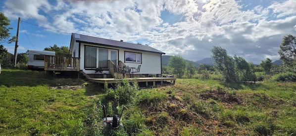 Une maison de plain-pied dotée d’une terrasse, d’un espace extérieur aménagé et couvert, et offrant une vue sur les montagnes.