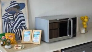 Keittiössä on mikroaaltouuni, astianpesukone ja keittiötasolla on kehystetty taulu.