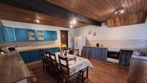 A kitchen with blue cabinets, a dining table with chairs, and a tiled floor. - The four Oaks rural holiday (Le Fleix)