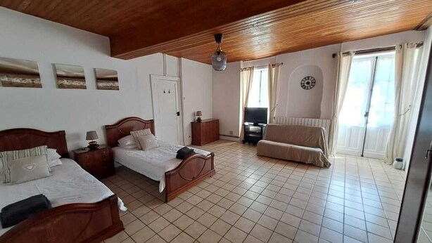 A bedroom with two beds, a sofa, a TV, and a clock on the wall. - The four Oaks rural holiday (Le Fleix)