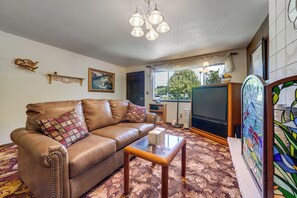 A living room with a leather sofa, a coffee table, a television, and a window with a view of the outdoors. - Private Yard & Patio! Pet-Friendly Lynnwood Home (Lynnwood)