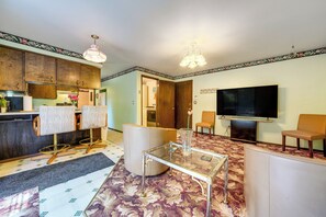 Sala de estar con televisión, asientos, una mesa de centro y una zona de cocina.