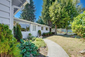 Ein eingeschossiges Haus mit einer Veranda, umgeben von üppiger Vegetation und blauem Himmel.