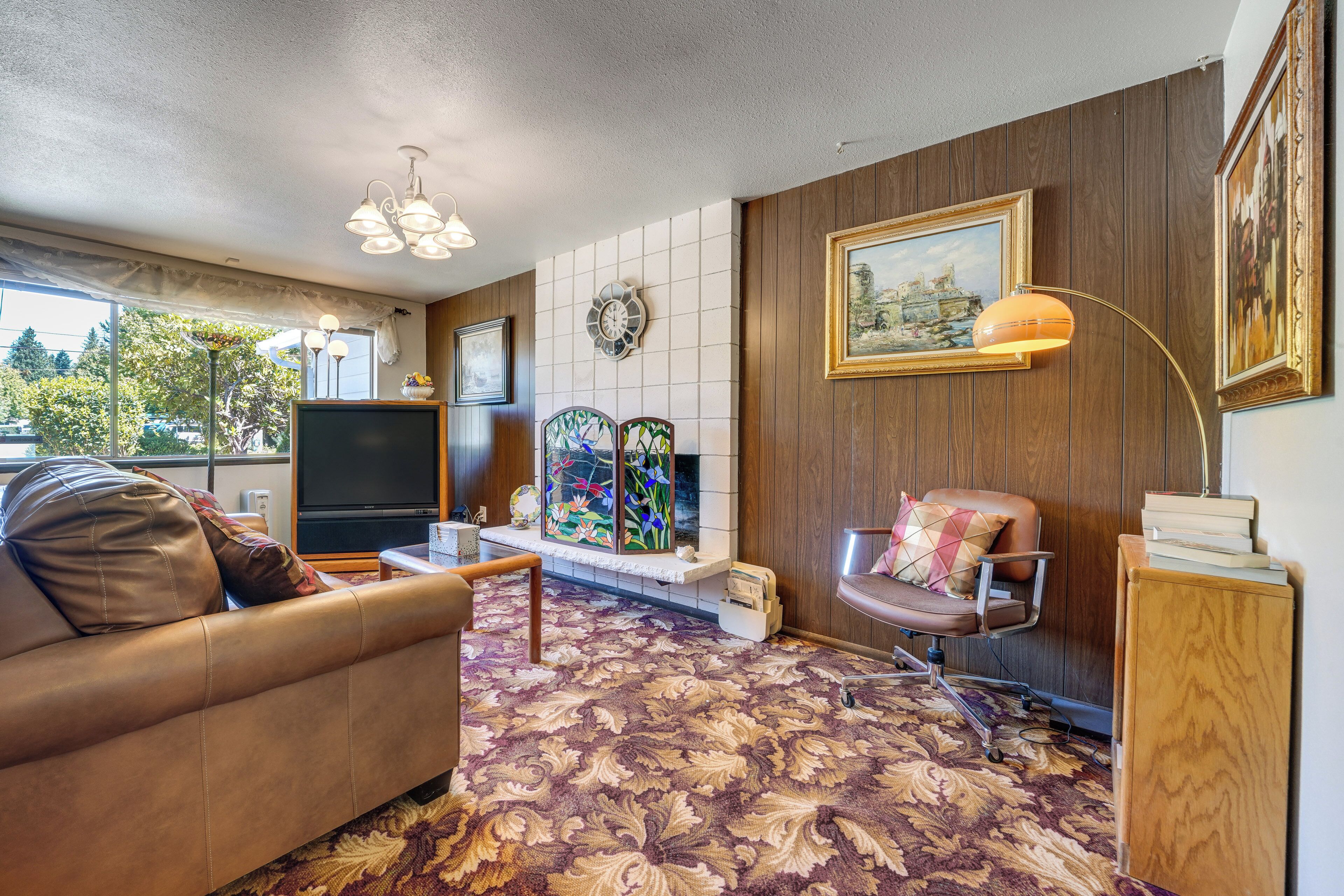 A living room with a sofa, a TV, a fireplace, and a painting on the wall.