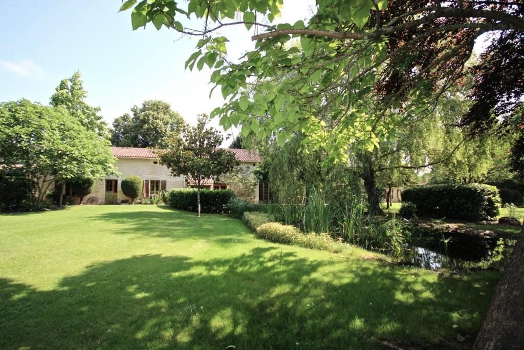 A well-maintained garden with a lawn, a small pond, and a building with a red-tiled roof.
