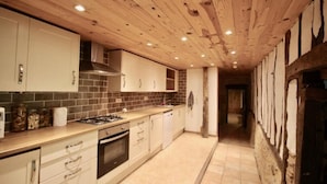 A kitchen with wooden ceiling beams, white cabinets, a gas stove, and a tiled backsplash. - Mulberry Lodge 16th Century farmhouse in rural setting (Le Fleix)