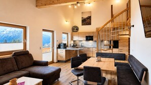 A modern interior with a wooden staircase, a dining area with a table and chairs, a kitchen with a microwave, and a sofa. - Stylish Apartment with Mountain Views (Mittersill)