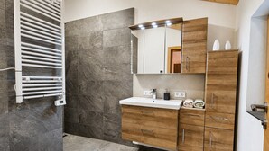 A bathroom with a white sink, wooden vanity, and a towel rack. - Stylish Apartment with Mountain Views (Mittersill)