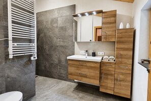 Ein Badezimmer mit einem weißen Waschbecken, einer Holz-Kommode und einem Handtuchhalter.