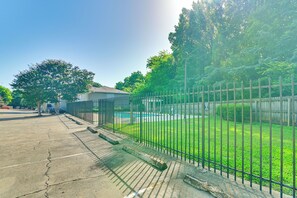 Une cour clôturée avec une piscine, un petit bâtiment et un espace de stationnement.