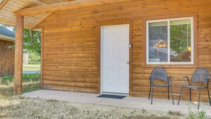 A wooden cabin with a white door, two metal chairs, and a window with a view of a house. - Mississippi River Basecamp! Studio 24 Mi to Winona (Cochrane)