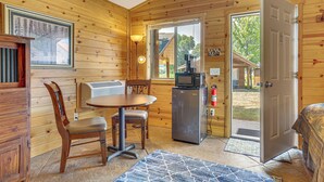 A compact room with a wooden interior, a dining table with chairs, a refrigerator, a television, and a door leading outside. - Mississippi River Basecamp! Studio 24 Mi to Winona (Cochrane)