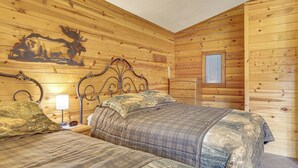 A wooden cabin room with two beds, a nightstand, a wall clock, and a window. - Mississippi River Basecamp! Studio 24 Mi to Winona (Cochrane)