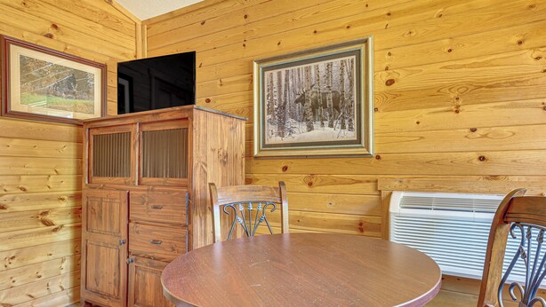 A wooden interior with a round table, a cabinet, and framed pictures on the walls. - Mississippi River Basecamp! Studio 24 Mi to Winona (Cochrane)
