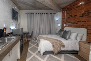 A compact hotel room with a bed, bedside table, and a small kitchenette. - The 260 Collection Luxury City Apartment (Johannesburg)
