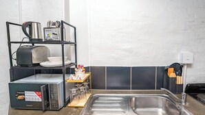 A kitchen with a stainless steel sink, a microwave, a toaster, and a shelf with utensils. - The 260 Collection Luxury City Apartment (Johannesburg)