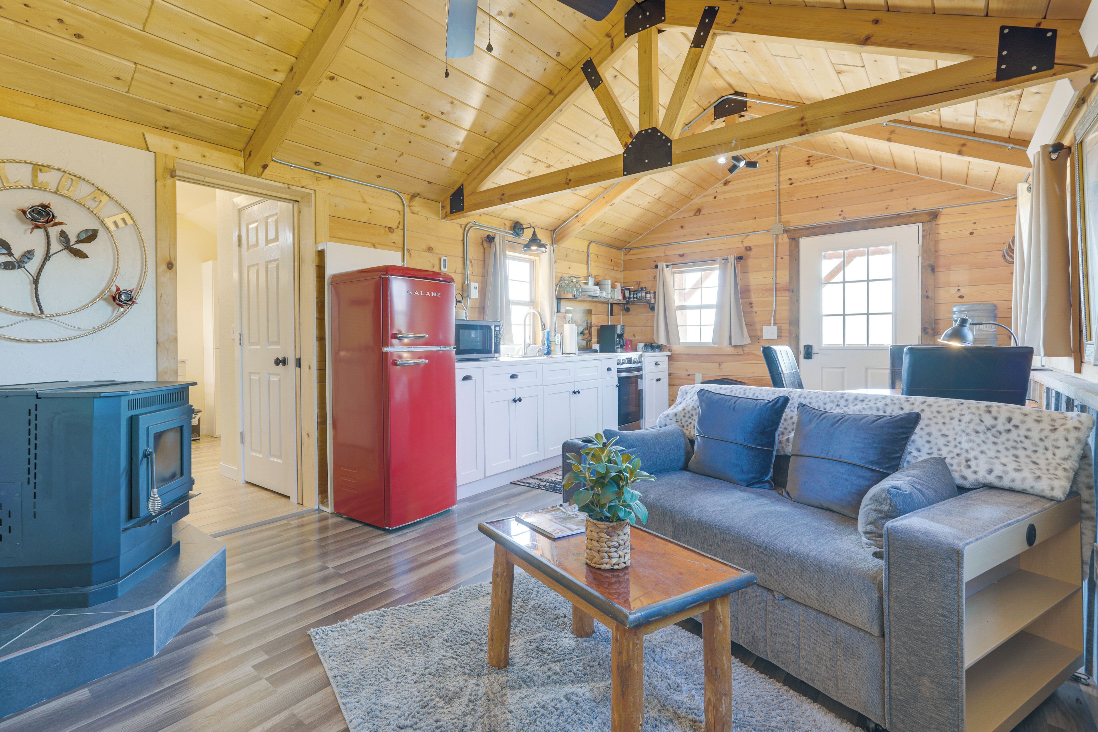 Ein gemütliches Blockhausschlafzimmer mit Holzbalkendecke, einem roten Kühlschrank, einer Küchenzeile, einem Sofa und einem blauen Fernseher.